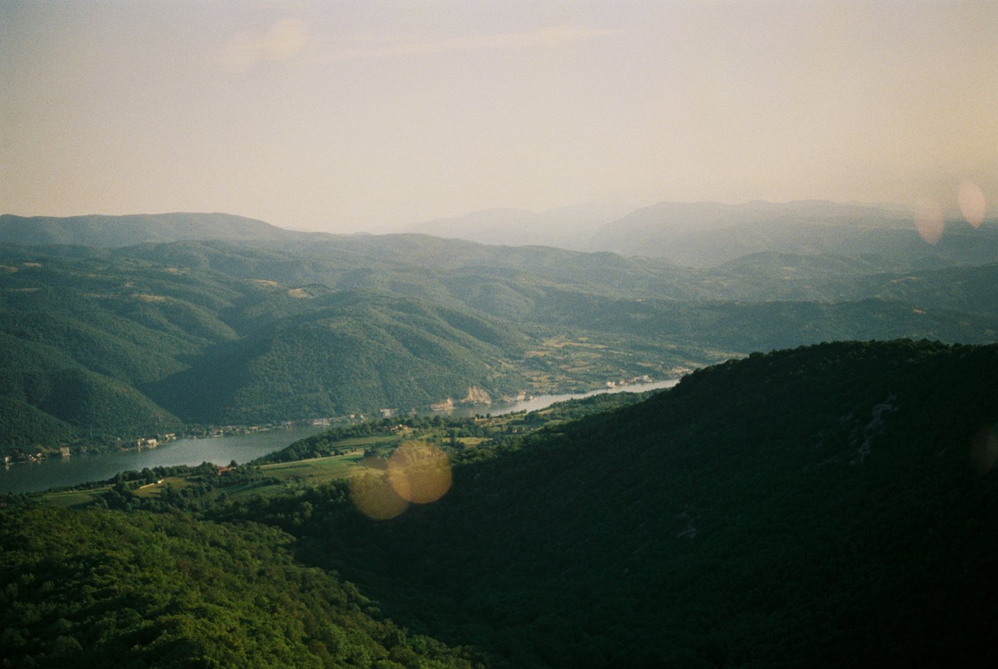A winding river flows through a valley surrounded by forested mountains.